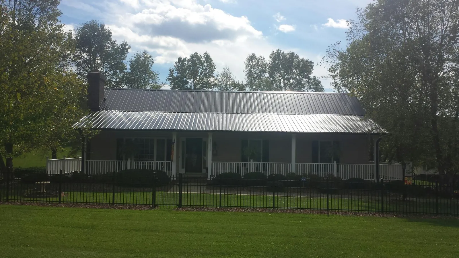 Gray metal roof on a brick ranch with a full width front porch — Gutter Guard Installation work by our crew in Langeloth