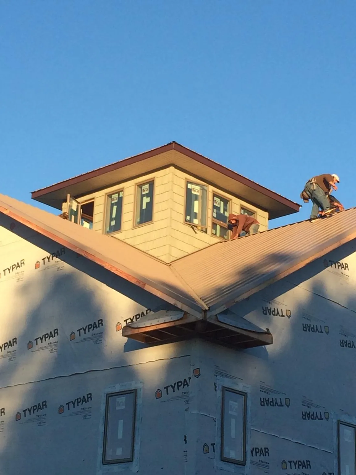 Roofers working around a rooftop cupola on a new metal roof at sunset — Roof Waterproofing in Langeloth by Roofing Brothers